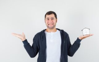 young-man-holding-house model one hand stretching another hand left