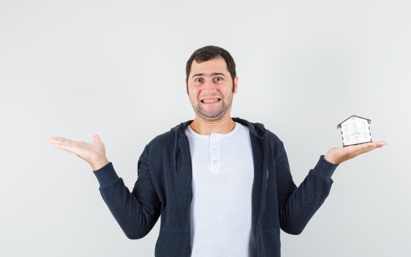 young-man-holding-house model one hand stretching another hand left